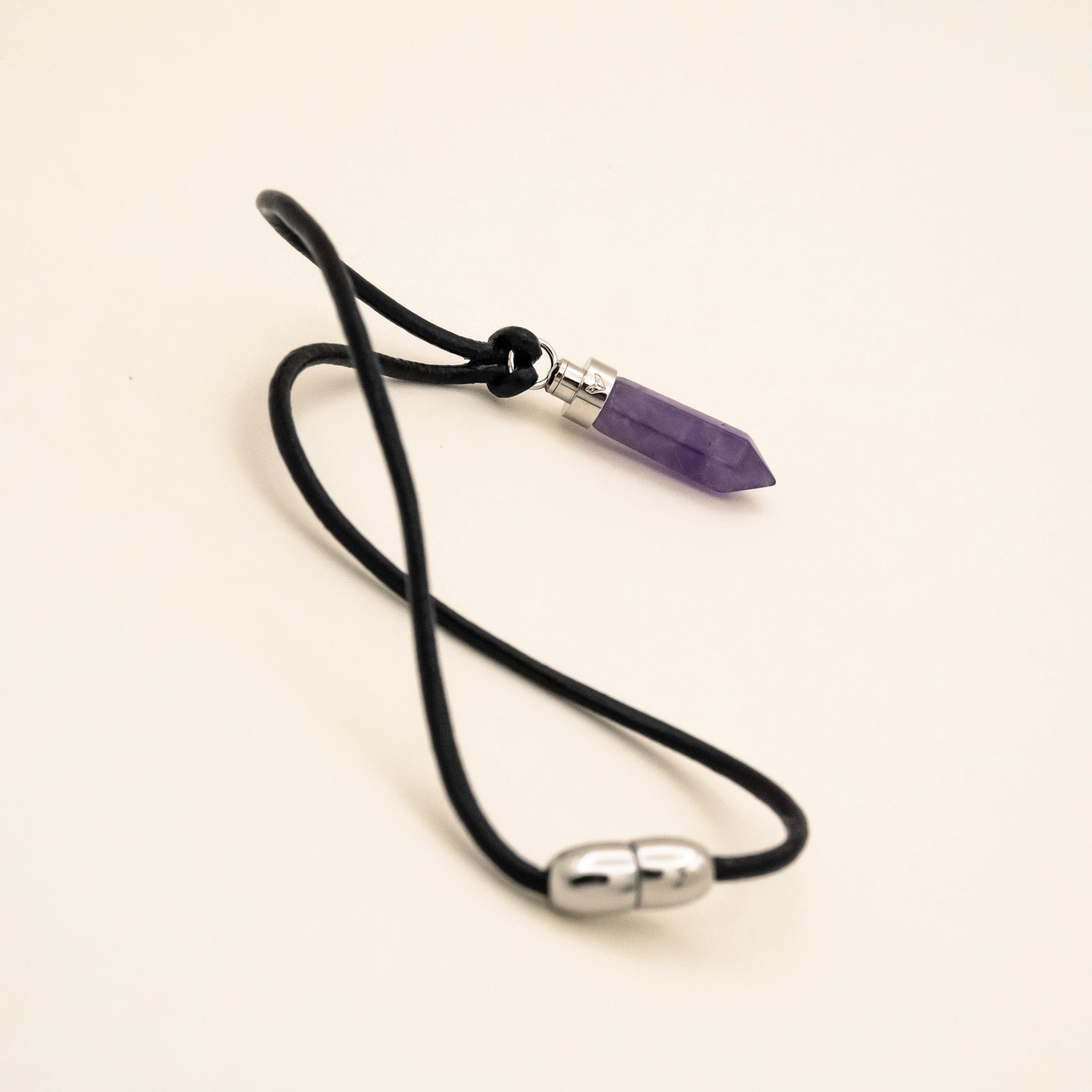 Amethyst calm pendant for cats on black leather cord with magnetic clasp on a beige background