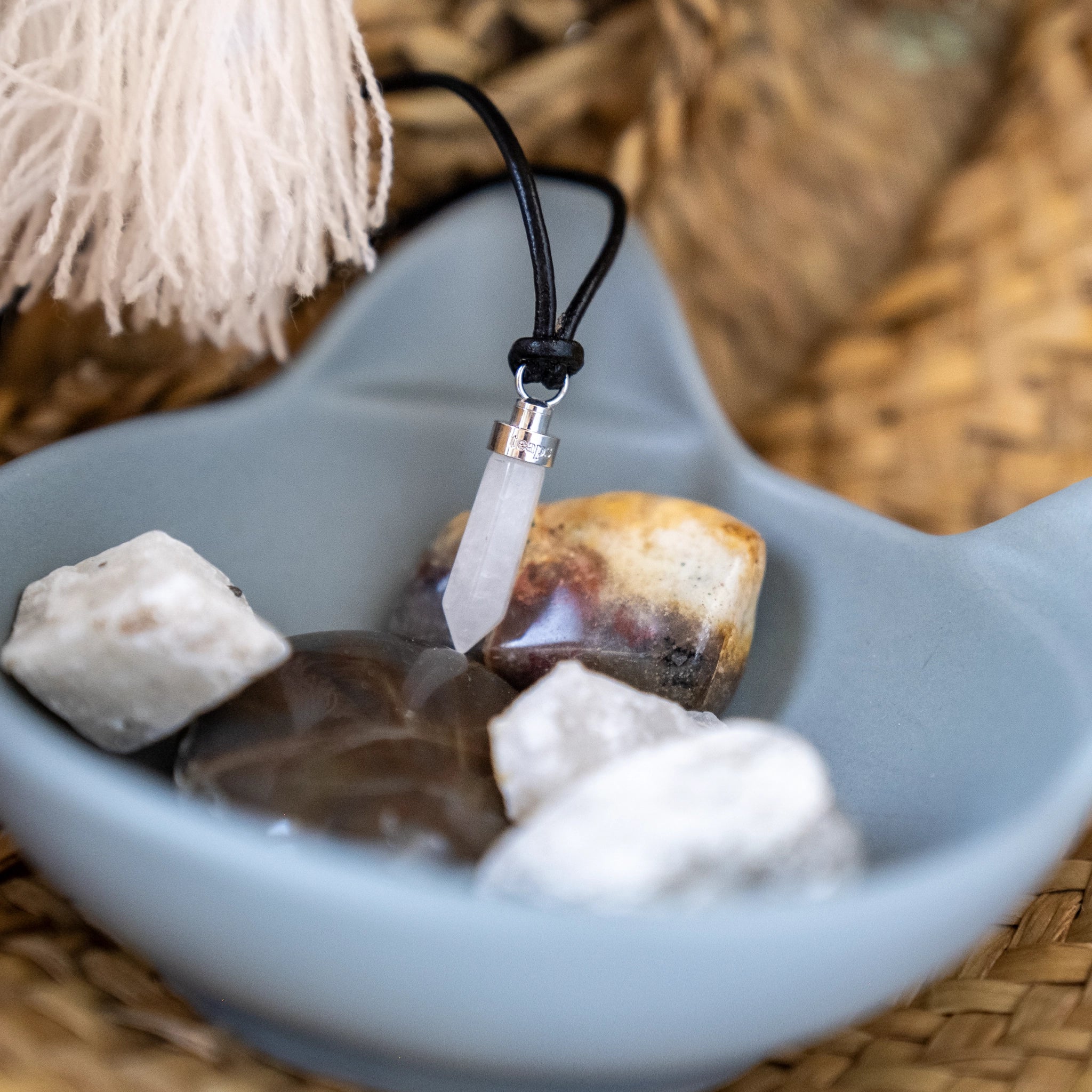 Clear quartz clarity pendant in blue bowl with raw quartz stones