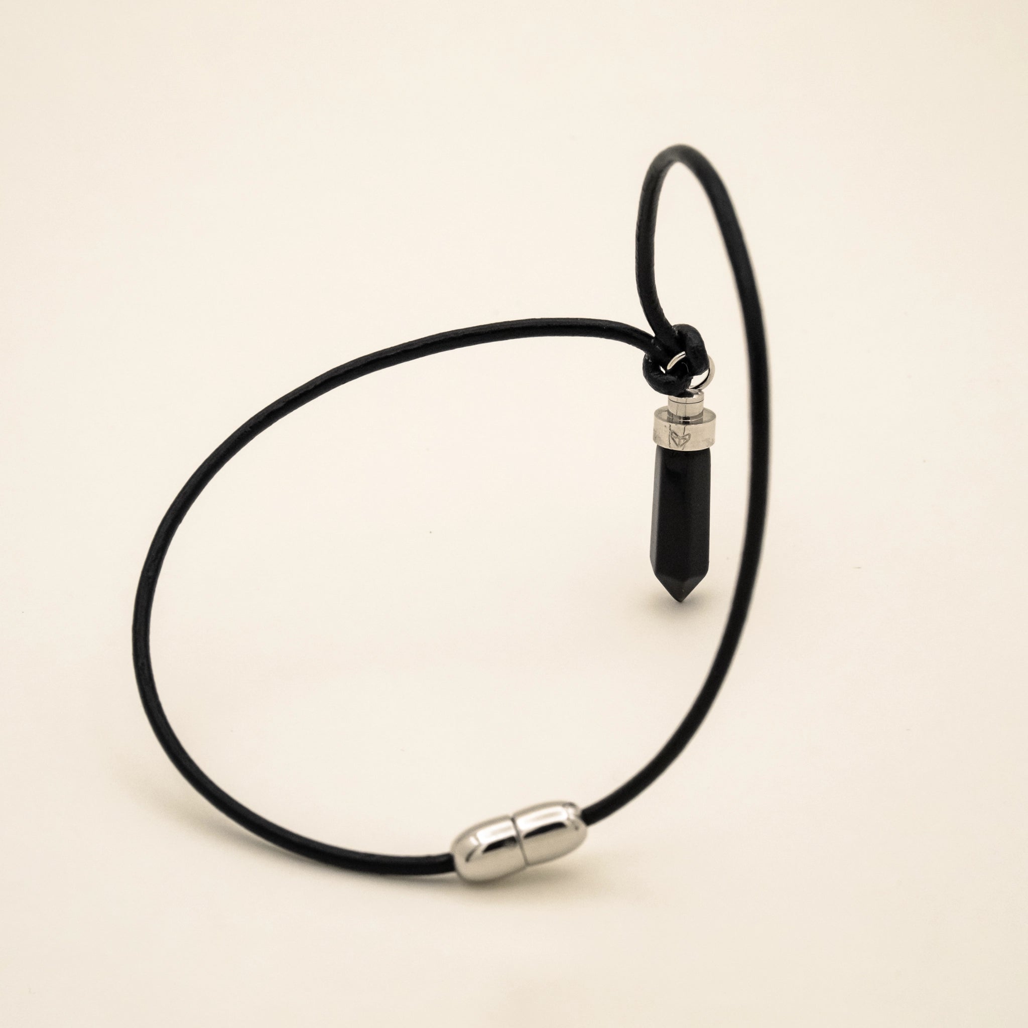 Obsidian protection pendant for cats on black leather cord with magnetic clasp on a beige background