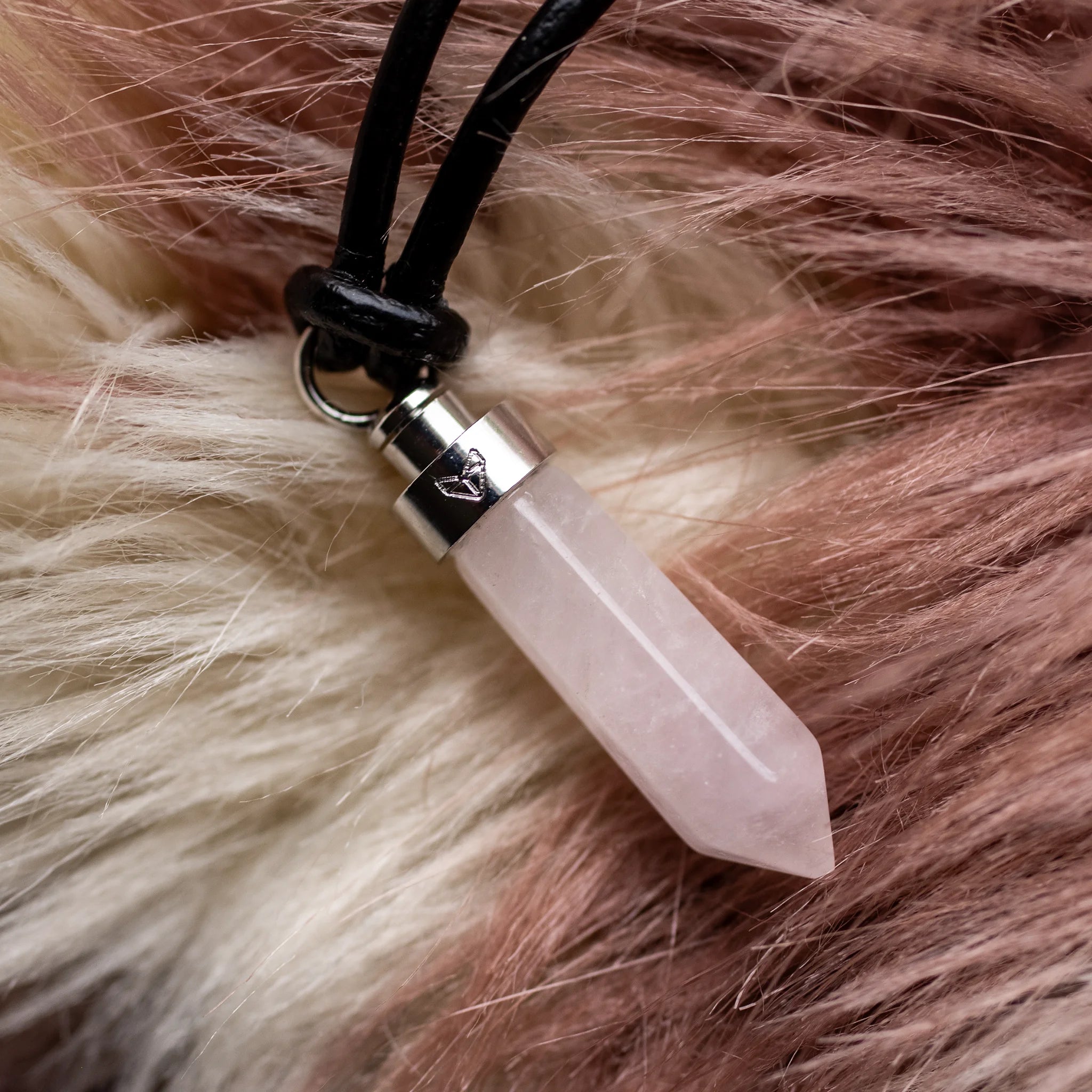 Close-up of rose quartz love pendant on soft fur blanket