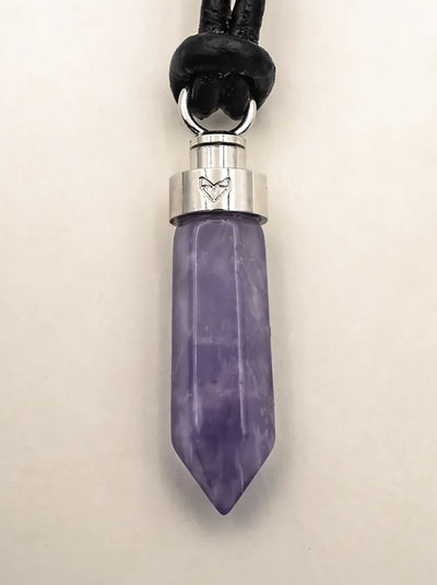 Close-up of amethyst calm pendant on black leather cord on a beige background