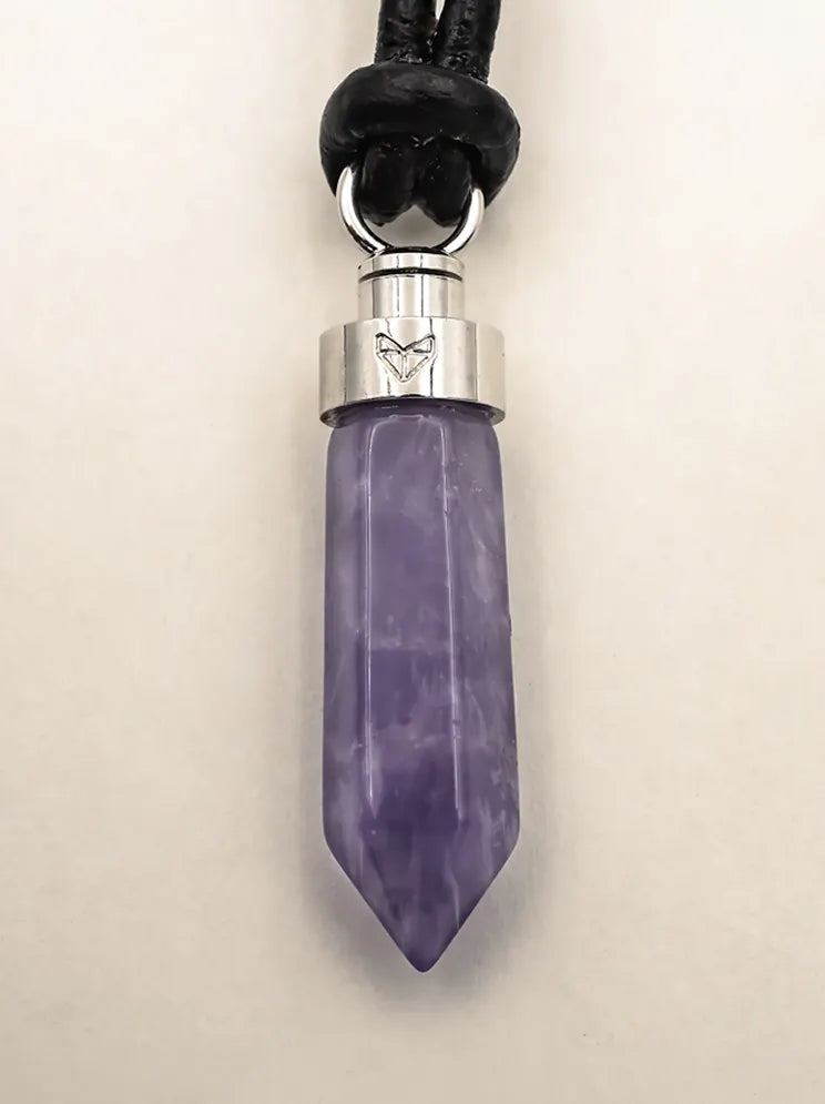 Close-up of amethyst calm pendant on black leather cord on a beige background