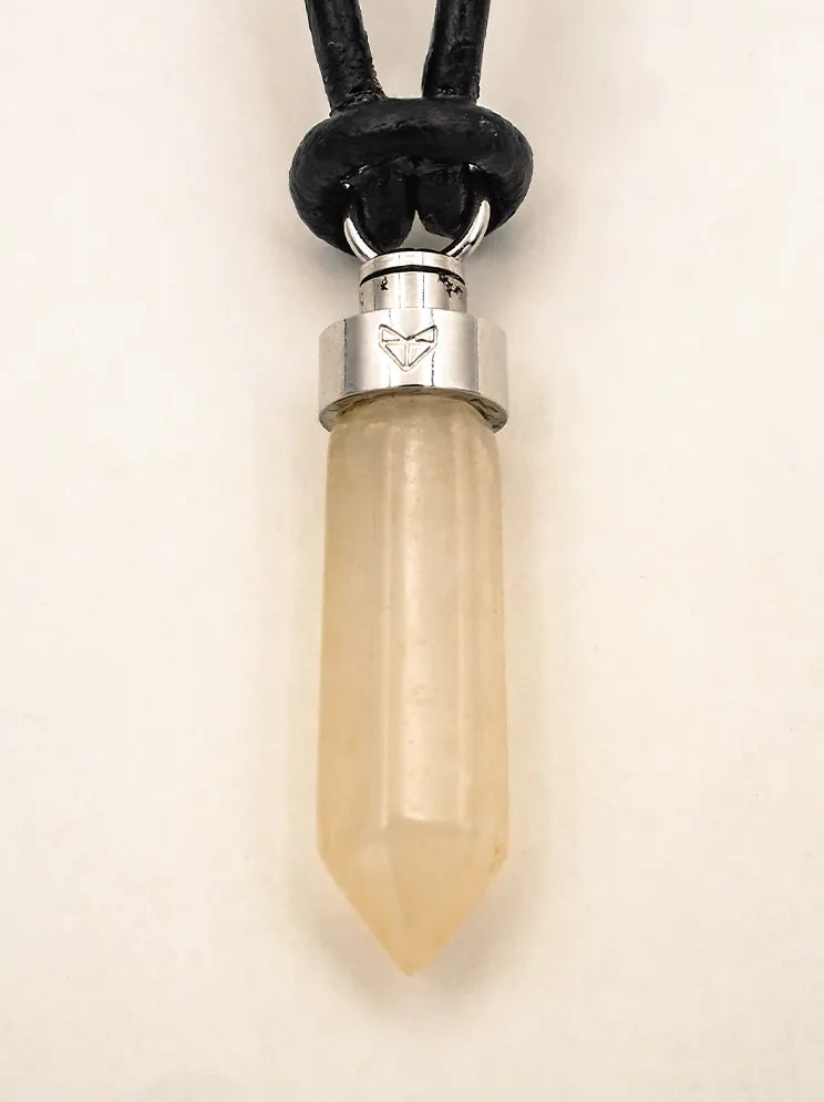 Close-up of citrine joy pendant on black leather cord on a beige background
