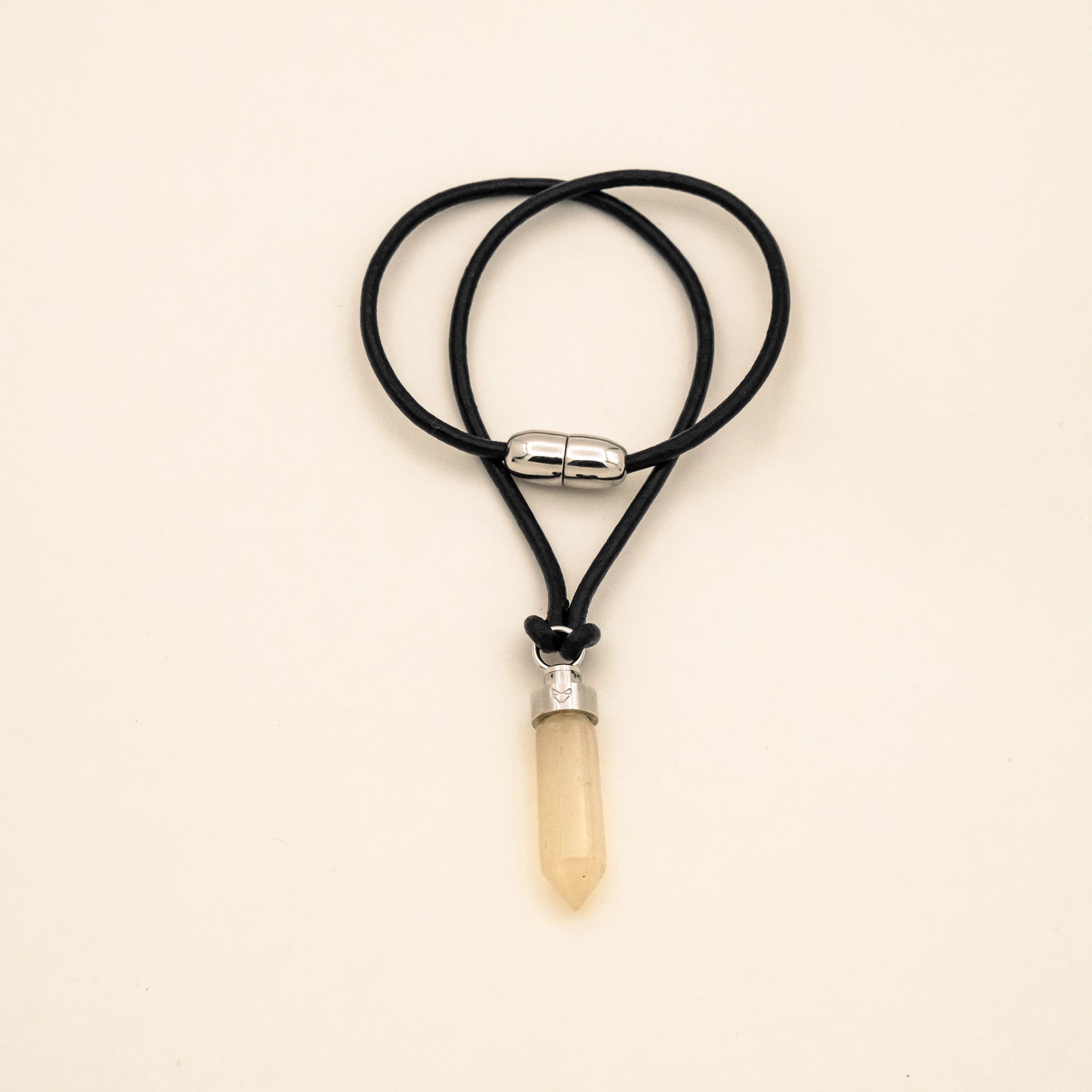 Citrine joy pendant for cats on black leather cord with magnetic clasp on a beige background
