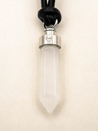 Close-up of clear quartz clarity pendant on black leather cord on a beige background