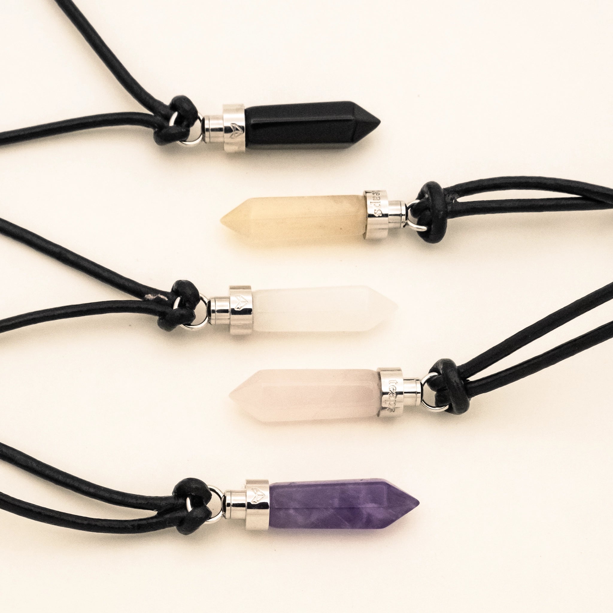 Crystal cat pendants laid flat showing obsidian, citrine, clear quartz, rose quartz, and amethyst