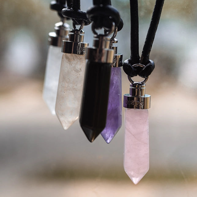 Crystal cat pendants hanging outdoors showing clear quartz, citrine, obsidian, amethyst, and rose quartz