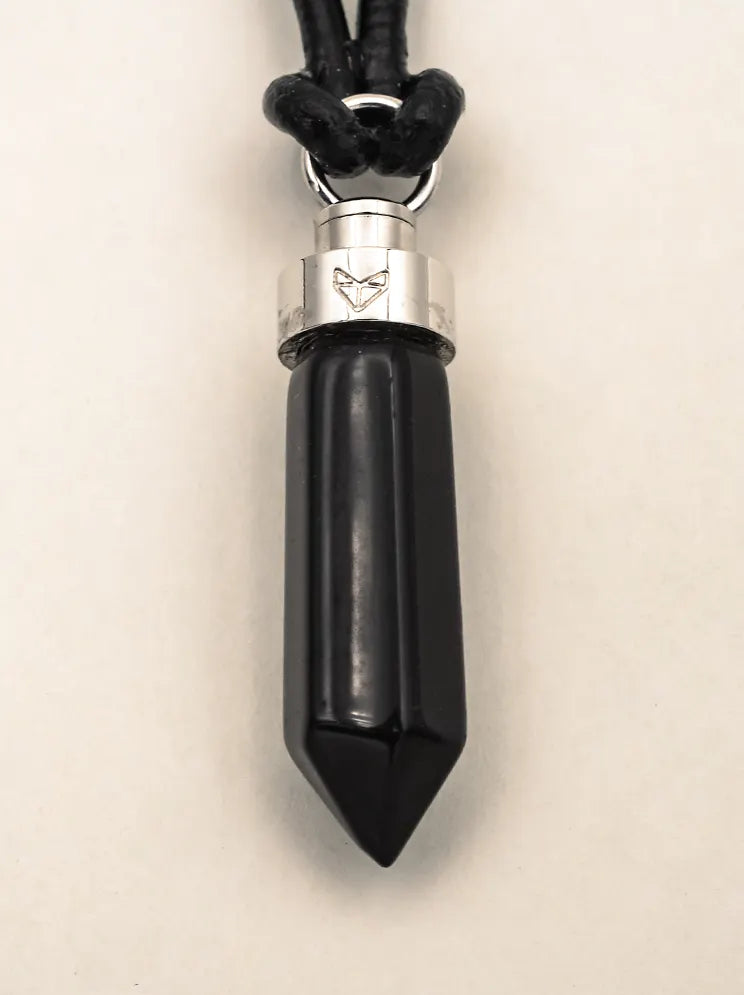 Close-up of obsidian protection pendant on black leather cord on a beige background