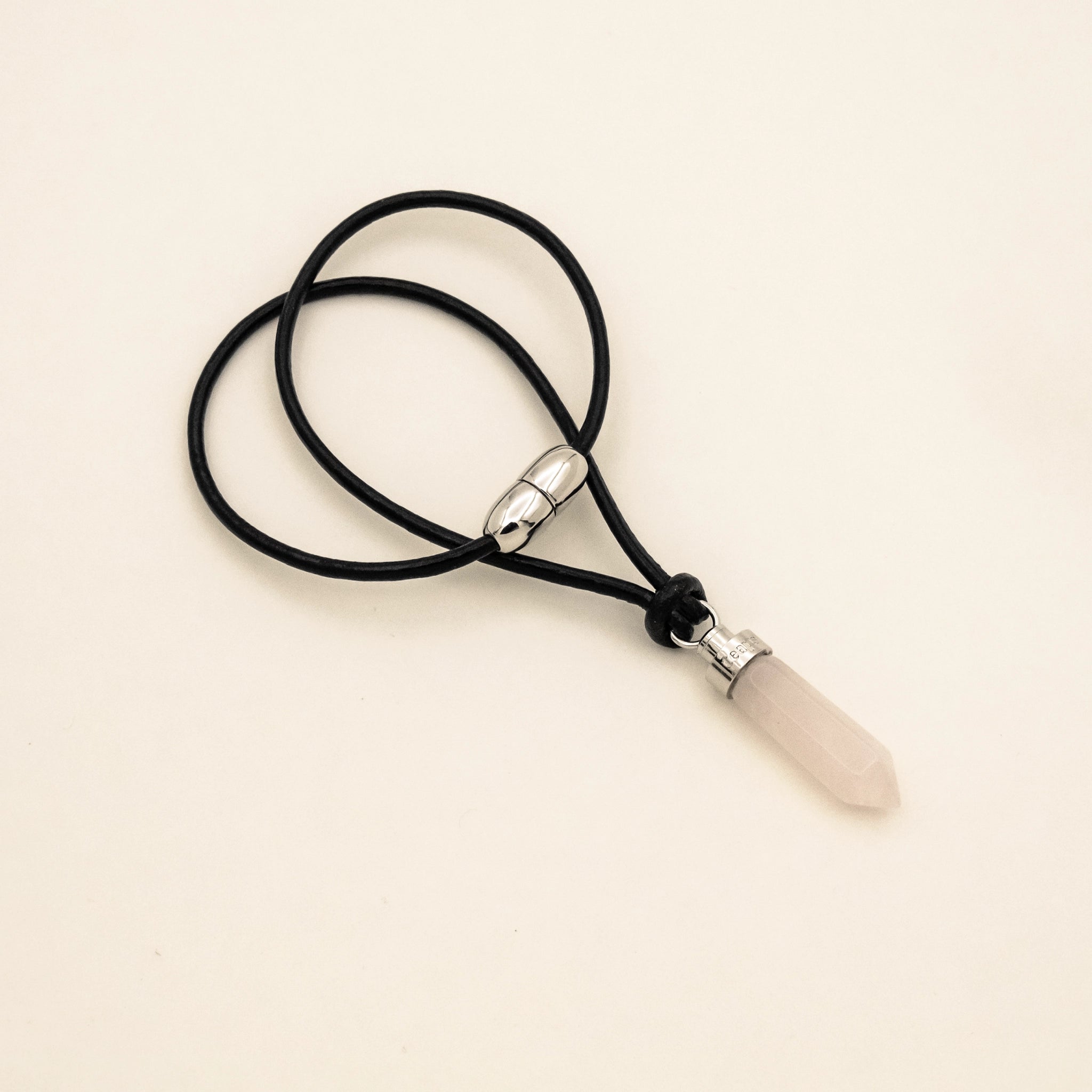 Rose quartz love pendant for cats on black leather cord with magnetic clasp on a beige background