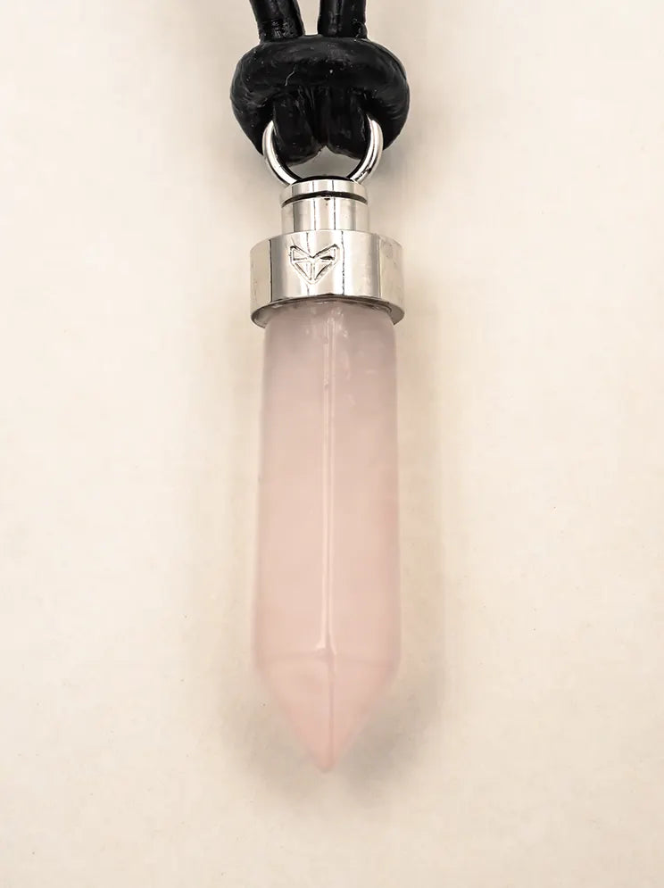 Close-up of rose quartz love pendant on black leather cord on a beige background